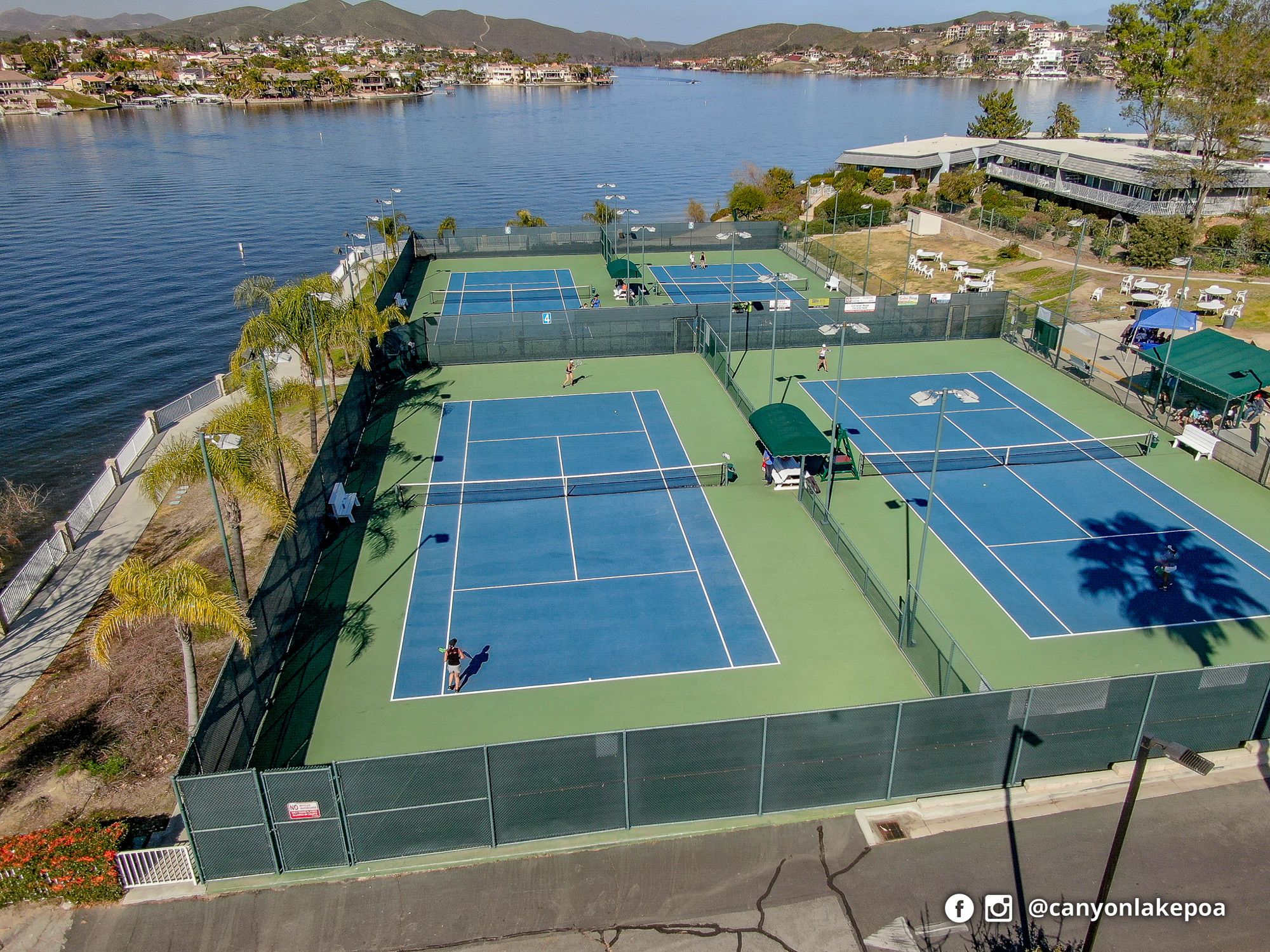 Canyon Lake tennis courts beside the lake and Lodge, with players on the blue and green courts.
