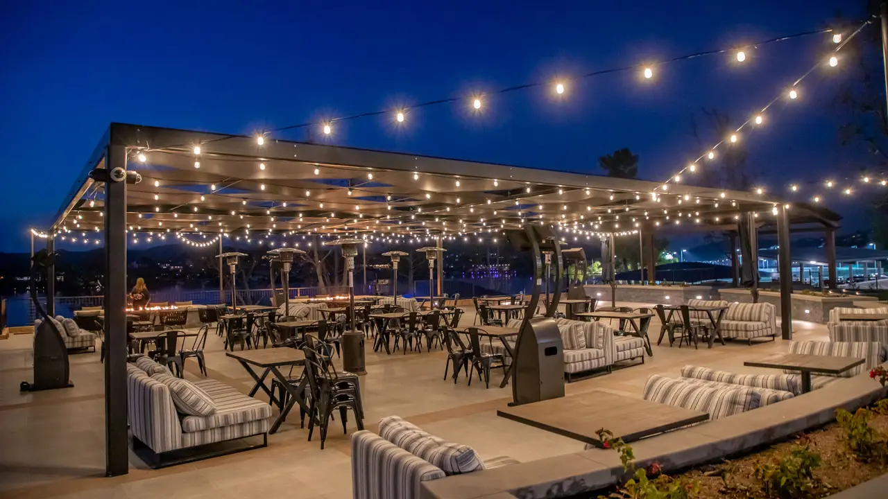 The Sunset Terrace at Canyon Lake Lodge at dusk, with string lights above outdoor tables and lounge seating.